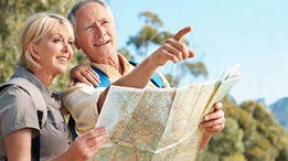 Older male and female holding a map and pointing off in the distance