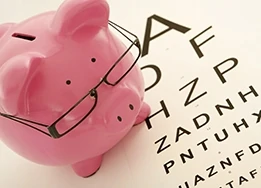 Piggy bank with glasses sat next to a eye test chart