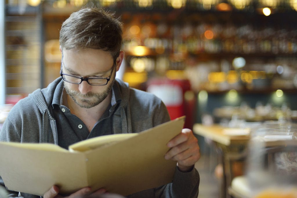 man in his 40s with presbyopia reading a restaurant menu