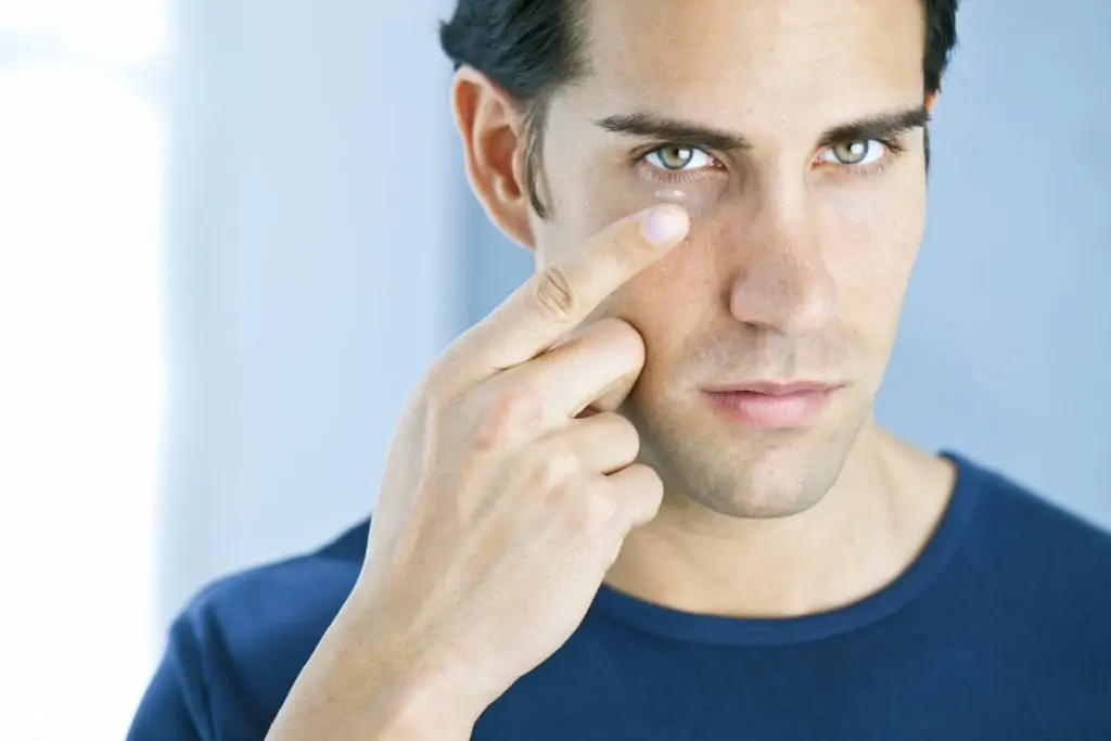 man putting in contact lens and dealing with contact lens problems