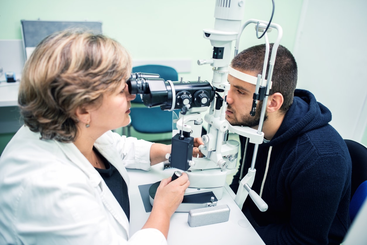 Woman performing eye test on man in blue hoodie